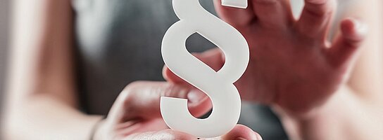 Jemand hält ein Paragraphenzeichen in den Händen